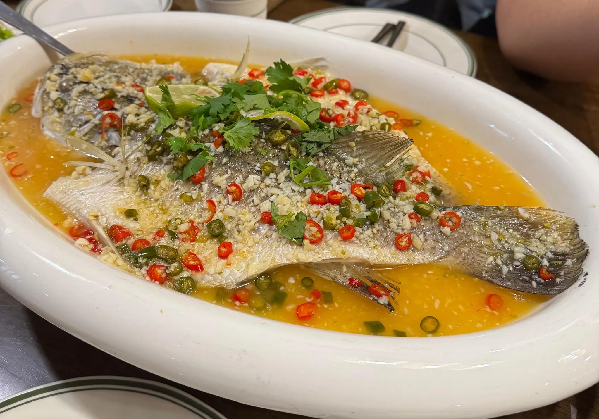 Whole steamed fish in a tangy lime, garlic and chili sauce, topped with coriander
