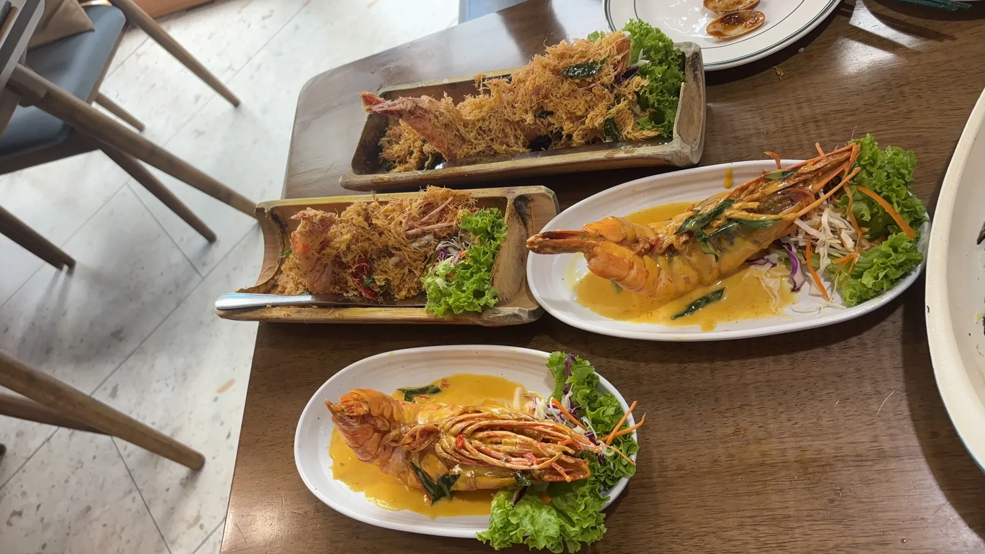A spread of prawn dishes — crispy cereal-butter prawns on boat plates and prawns in a golden creamy sauce