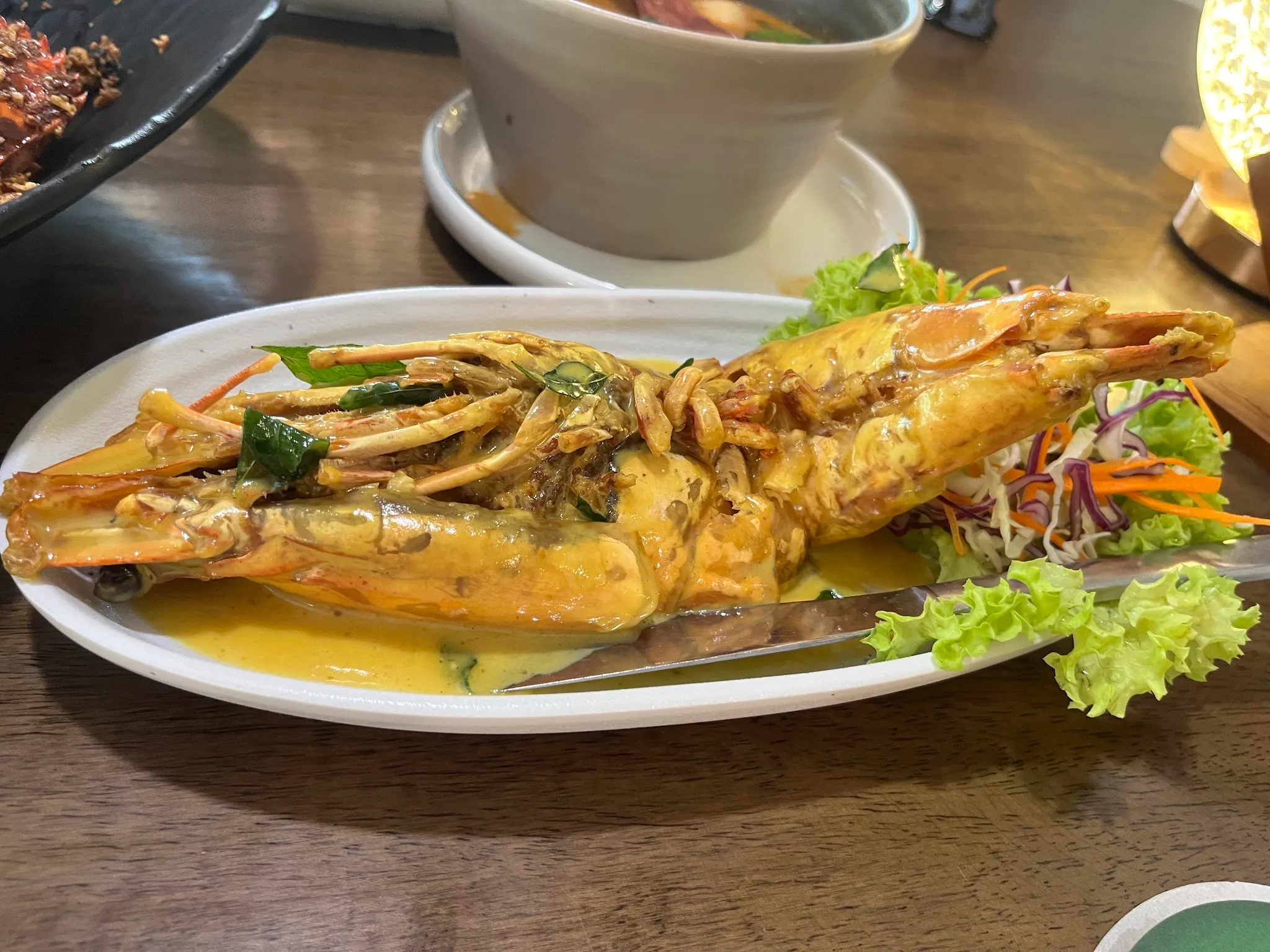 Large river prawns split and coated in a golden creamy butter sauce, with salad