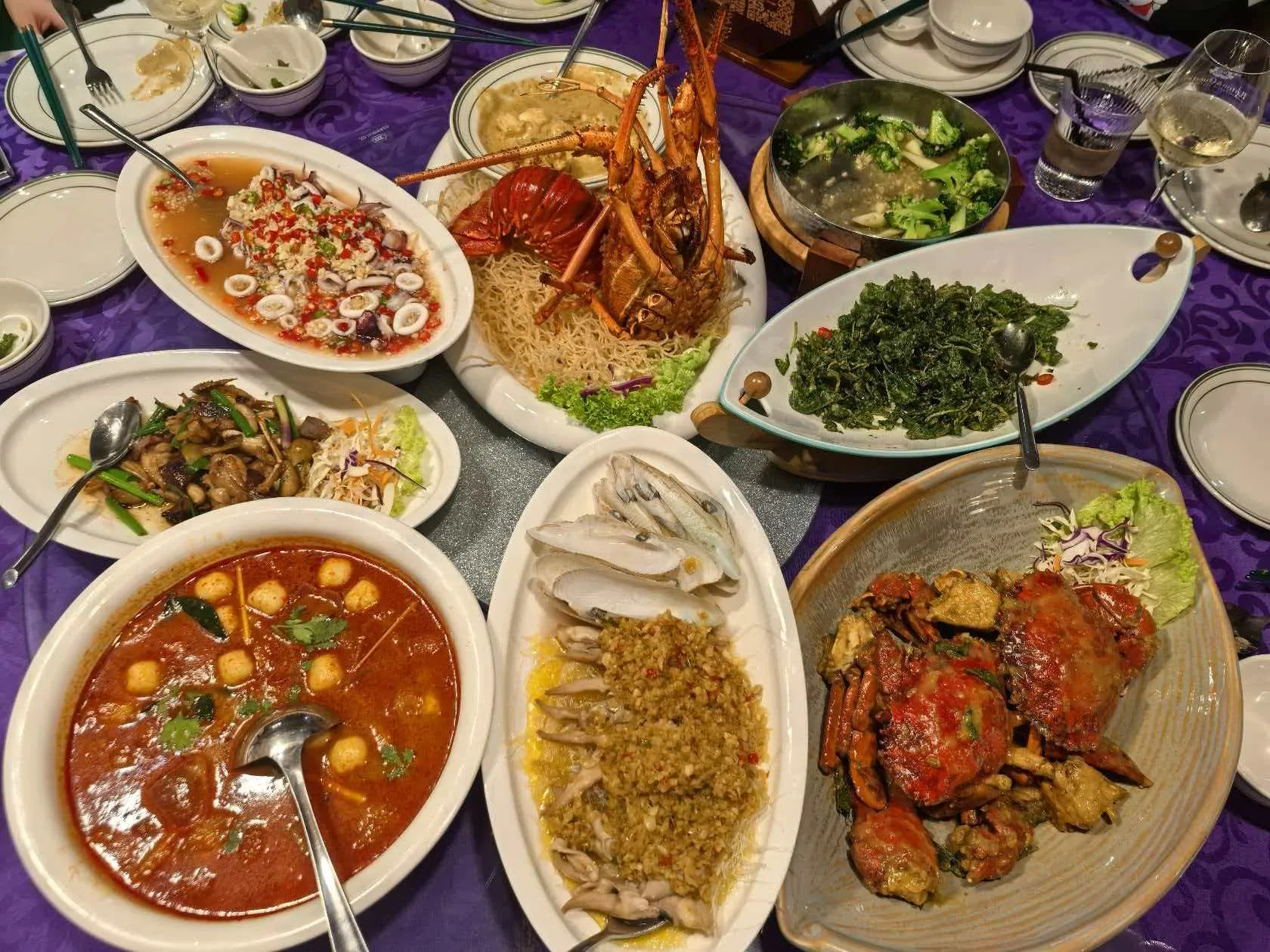 A seafood banquet spread — lobster on crispy vermicelli, crab in house sauce, tom yum, squid salad, greens and more