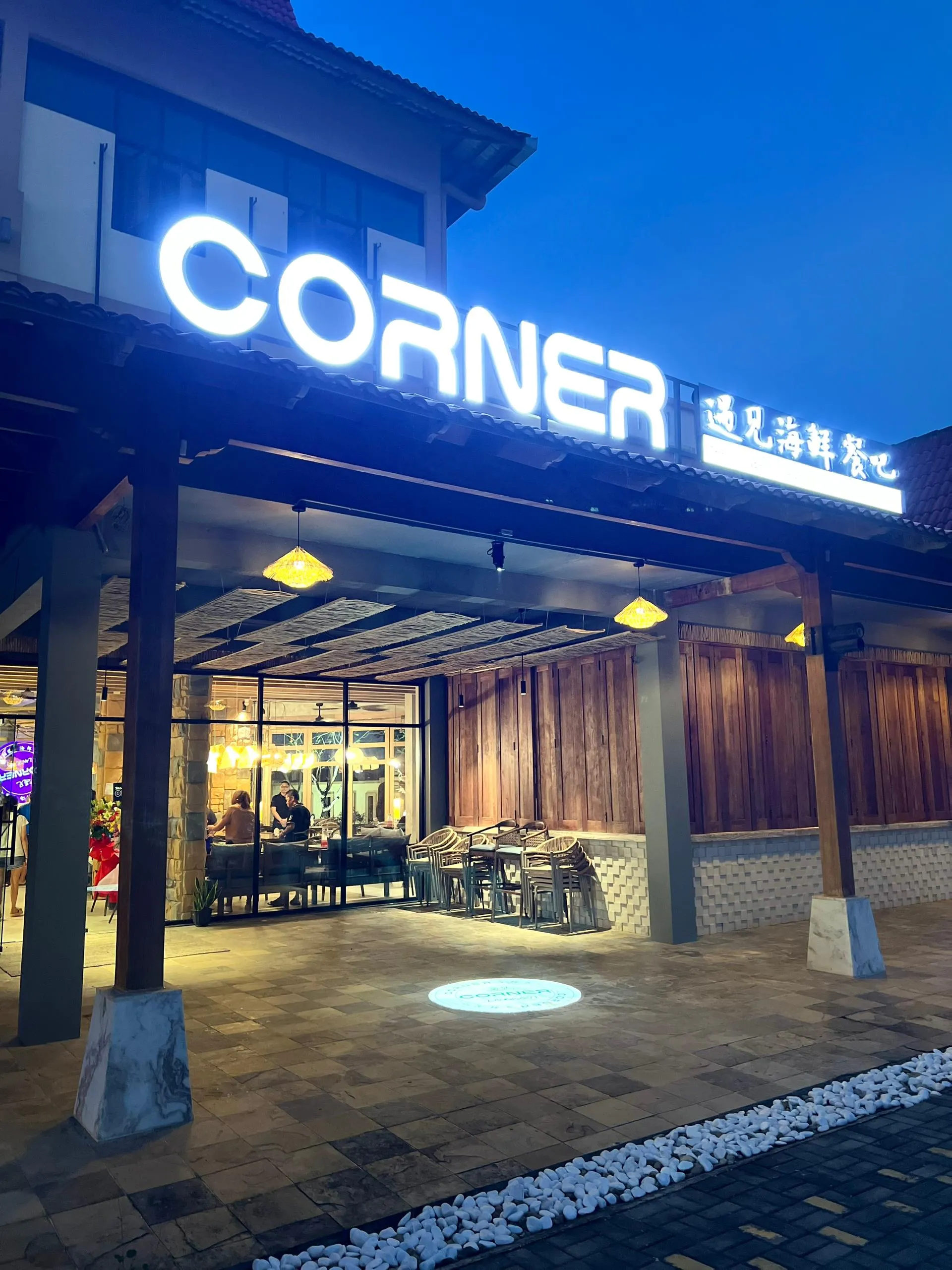 The Corner Seafood Restaurant storefront at blue hour — illuminated CORNER 遇见海鲜餐吧 sign over the terrace